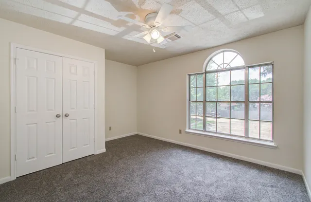 an empty room with windows and ceiling fan