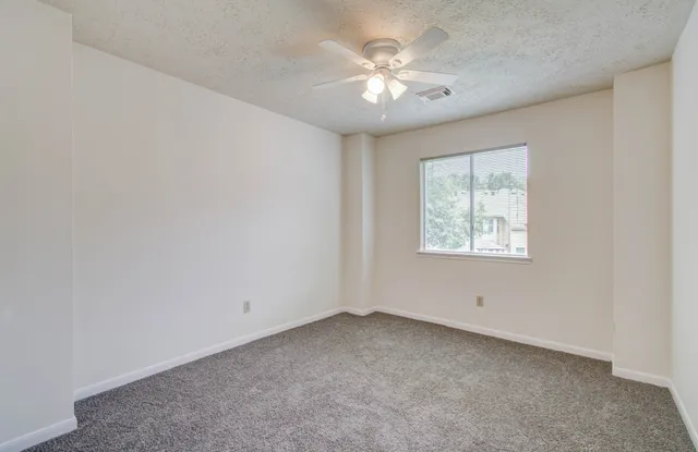 an empty room with a chandelier fan and windows