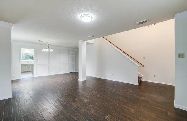 a view of an empty room with wooden floor and staircase