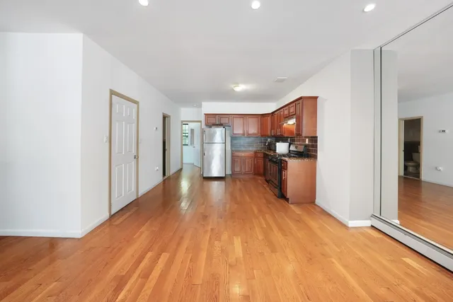 a view of a kitchen with refrigerator and wooden floor