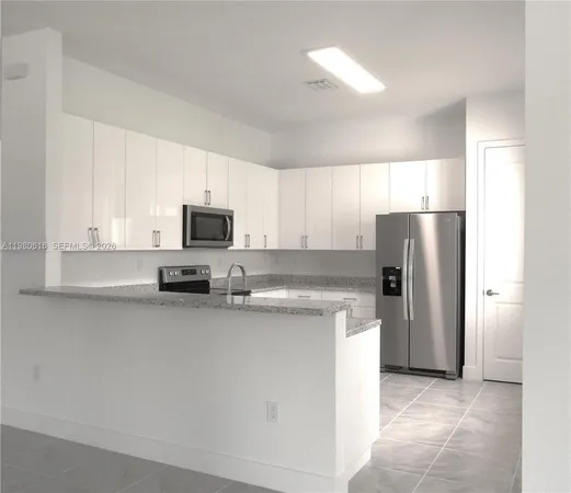 a kitchen with stainless steel appliances granite countertop a refrigerator a stove a sink and a microwave
