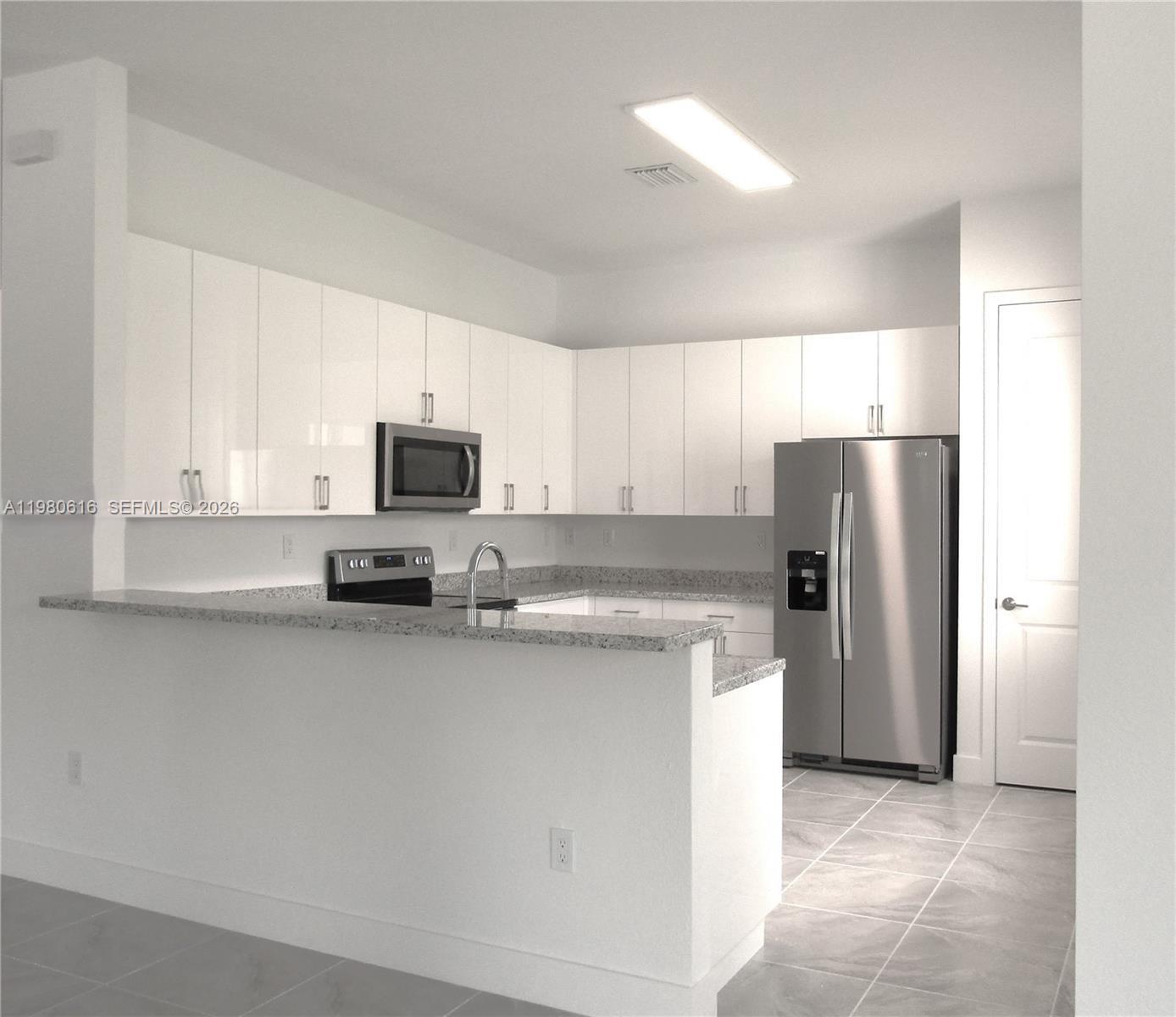 11998 Southwest 232nd Street Miami, FL 33170 - Photo 4 of 26 a kitchen with stainless steel appliances granite countertop a refrigerator a stove a sink and a microwave