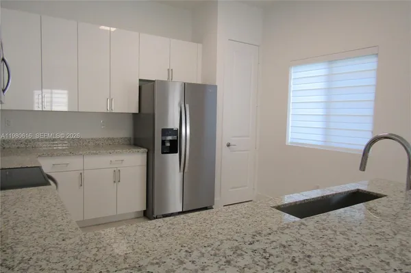 a kitchen with granite countertop a refrigerator sink and cabinets