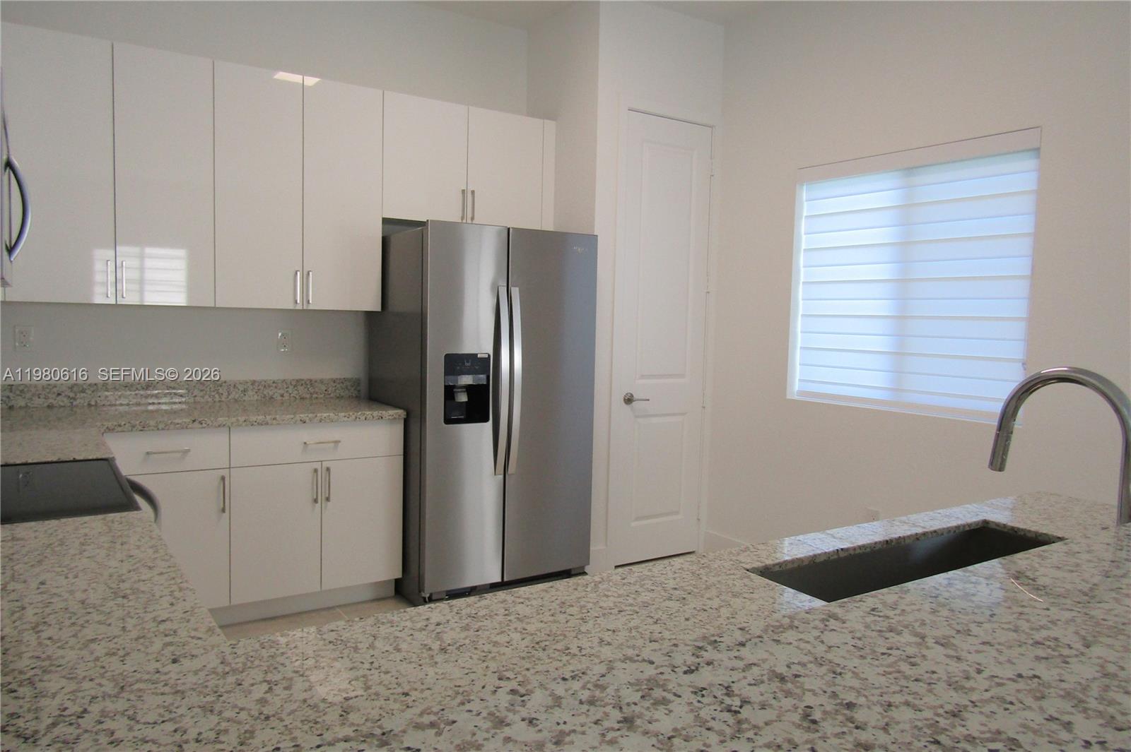 11998 Southwest 232nd Street Miami, FL 33170 - Photo 5 of 26 a kitchen with granite countertop a refrigerator sink and cabinets