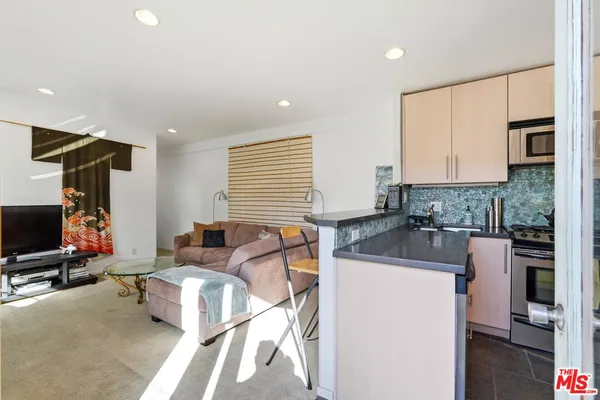 a kitchen with a sink cabinets and a flat screen tv