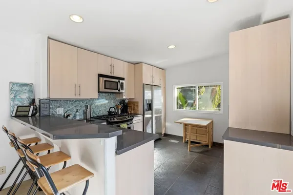 a kitchen with a dining table chairs and refrigerator