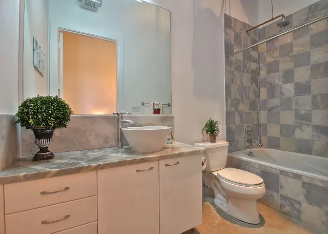 a bathroom with a granite countertop sink toilet a mirror and bathtub