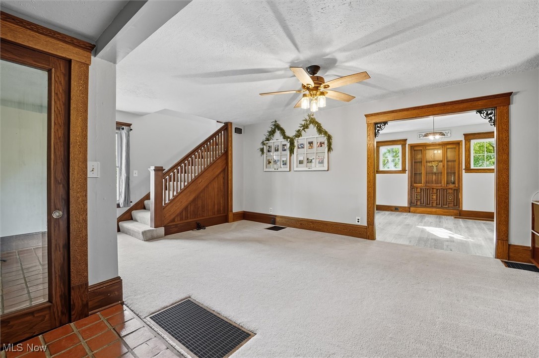 10536 Johnnycake Ridge Road Painesville, OH 44077 - Photo 12 of 40 Unfurnished living room featuring carpet, stairway, a textured ceiling, and a ceiling fan