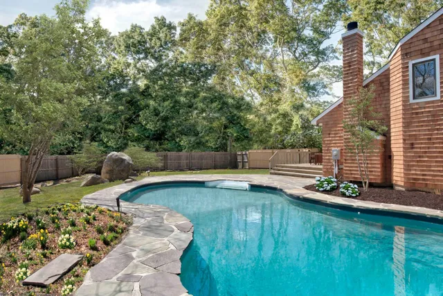 a view of a backyard with chairs and potted plants