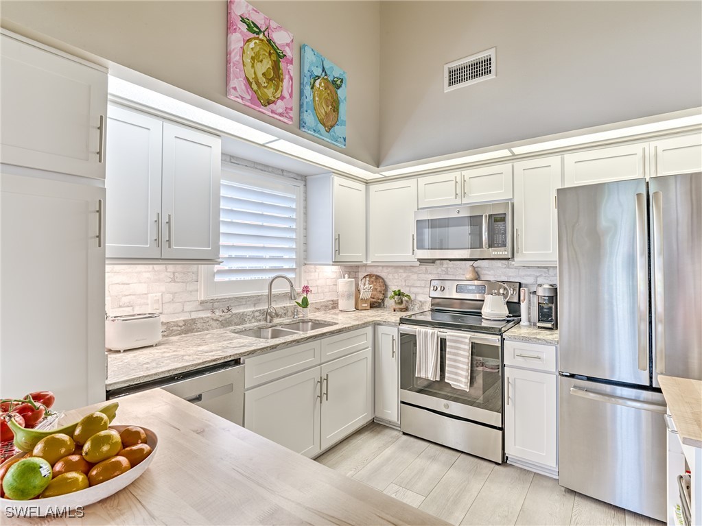 14981 Rivers Edge Court, Unit 228 Fort Myers, FL 33908 - Photo 13 of 40 a kitchen with stainless steel appliances granite countertop a sink a stove a refrigerator and cabinets