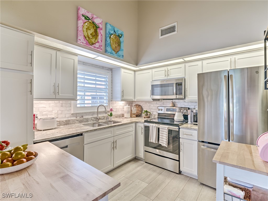 14981 Rivers Edge Court, Unit 228 Fort Myers, FL 33908 - Photo 14 of 40 a kitchen with stainless steel appliances a stove a sink and a refrigerator
