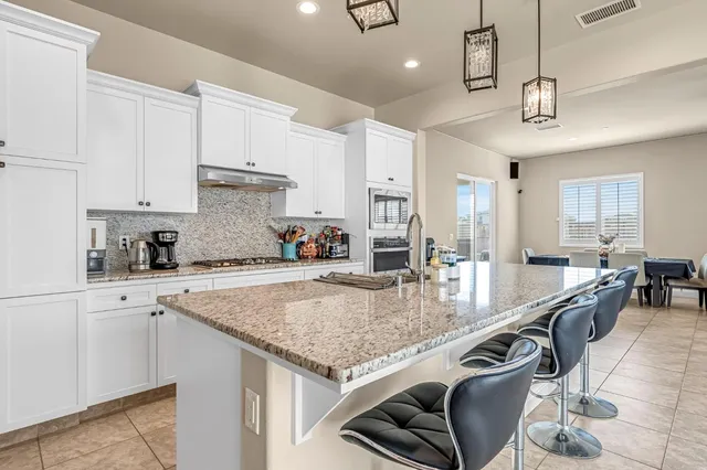 a kitchen with stainless steel appliances granite countertop a stove top oven a sink a counter space and cabinets
