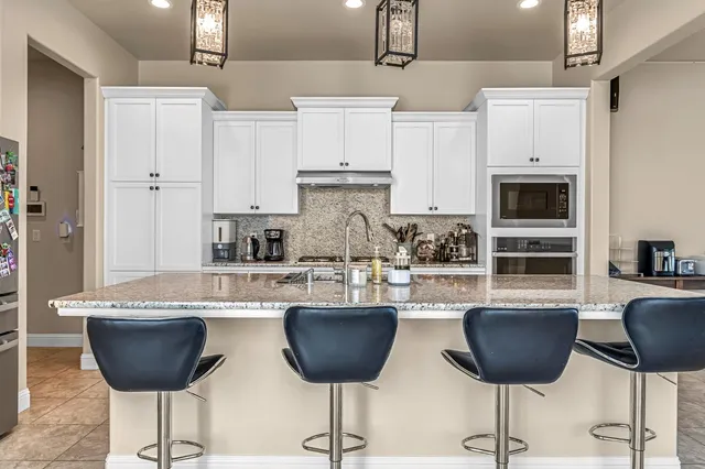 a kitchen with stainless steel appliances granite countertop a stove a sink a refrigerator and a dining table with wooden floor