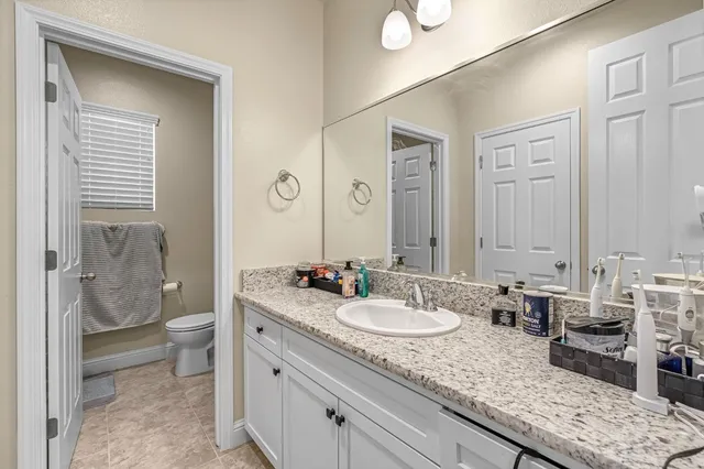a bathroom with a granite countertop sink a toilet and a mirror