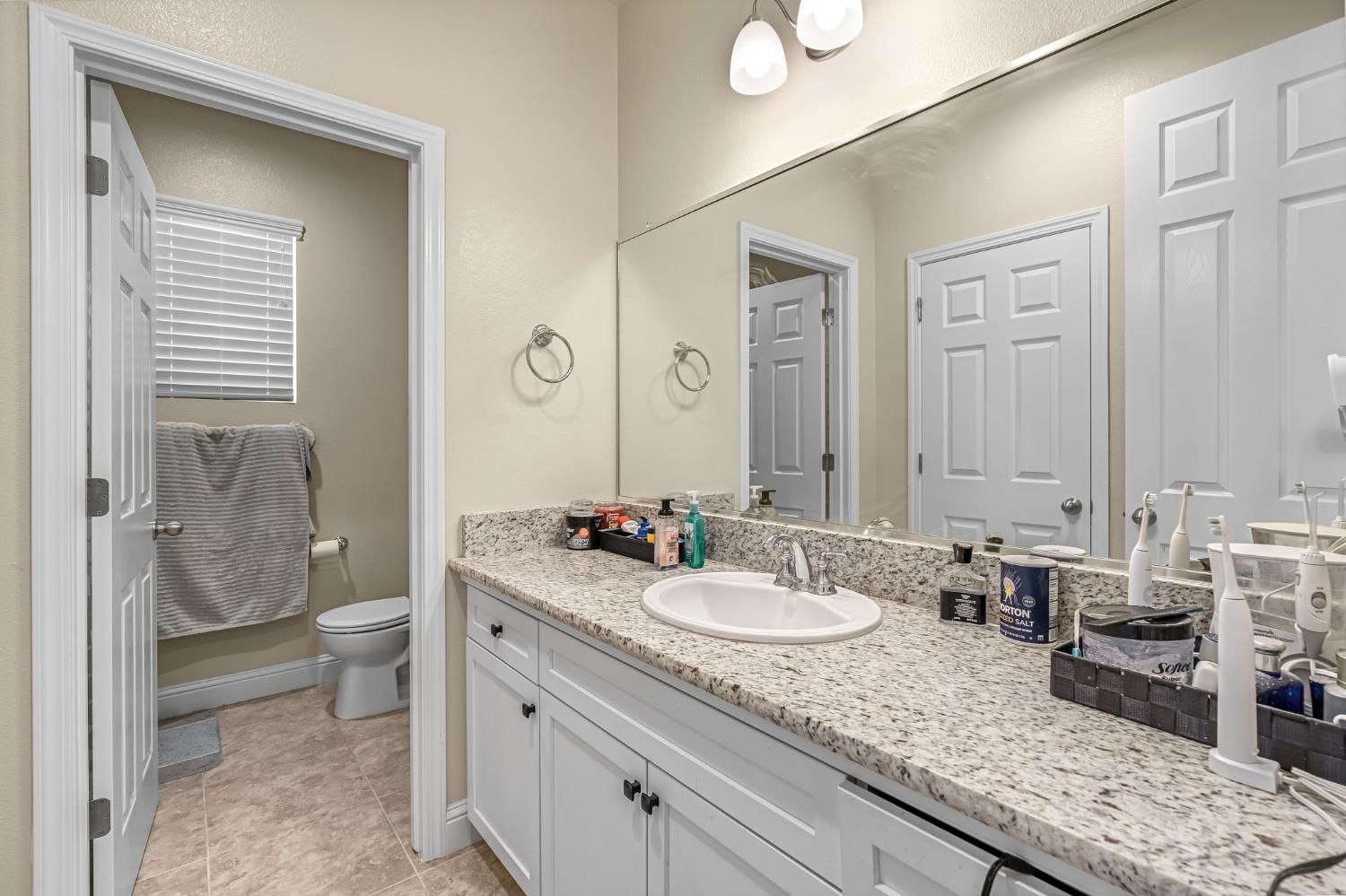 2468 Montana Avenue Clovis, CA 93619 - Photo 24 of 33 a bathroom with a granite countertop sink a toilet and a mirror