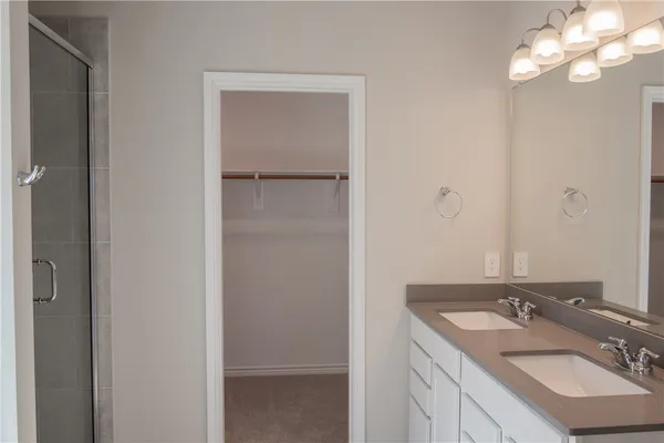an empty room with kitchen view and a chandelier fan