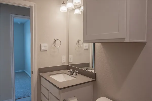 a white toilet sitting next to a bathroom sink and vanity