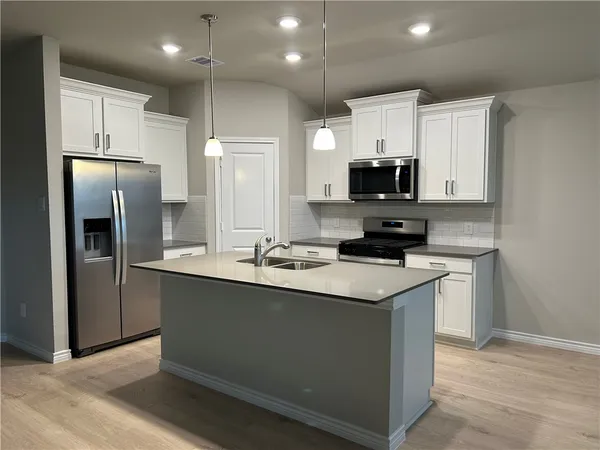 a kitchen with stainless steel appliances granite countertop a stove a refrigerator a sink and a microwave
