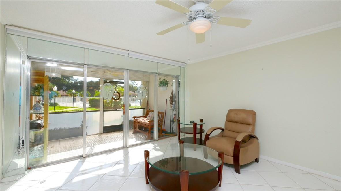 3930 Inverrary Boulevard, Unit 105D Lauderhill, FL 33319 - Photo 3 of 46 a living room with furniture a lamp and a floor to ceiling window
