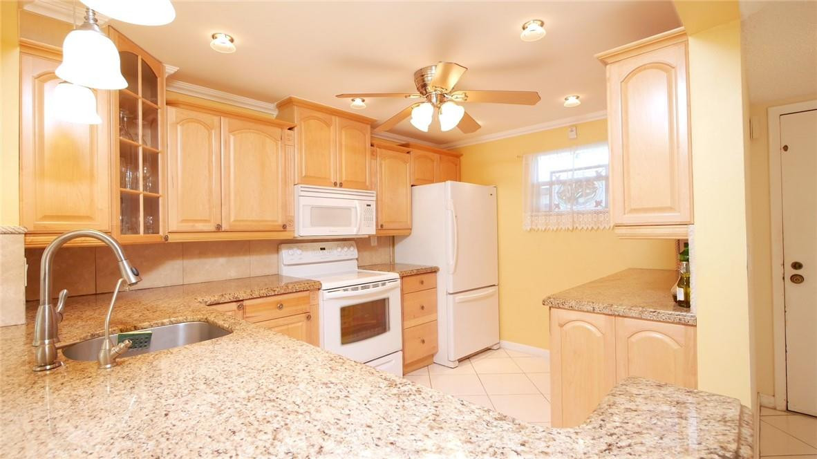 3930 Inverrary Boulevard, Unit 105D Lauderhill, FL 33319 - Photo 10 of 46 a kitchen with stainless steel appliances kitchen island granite countertop a refrigerator and a stove top oven