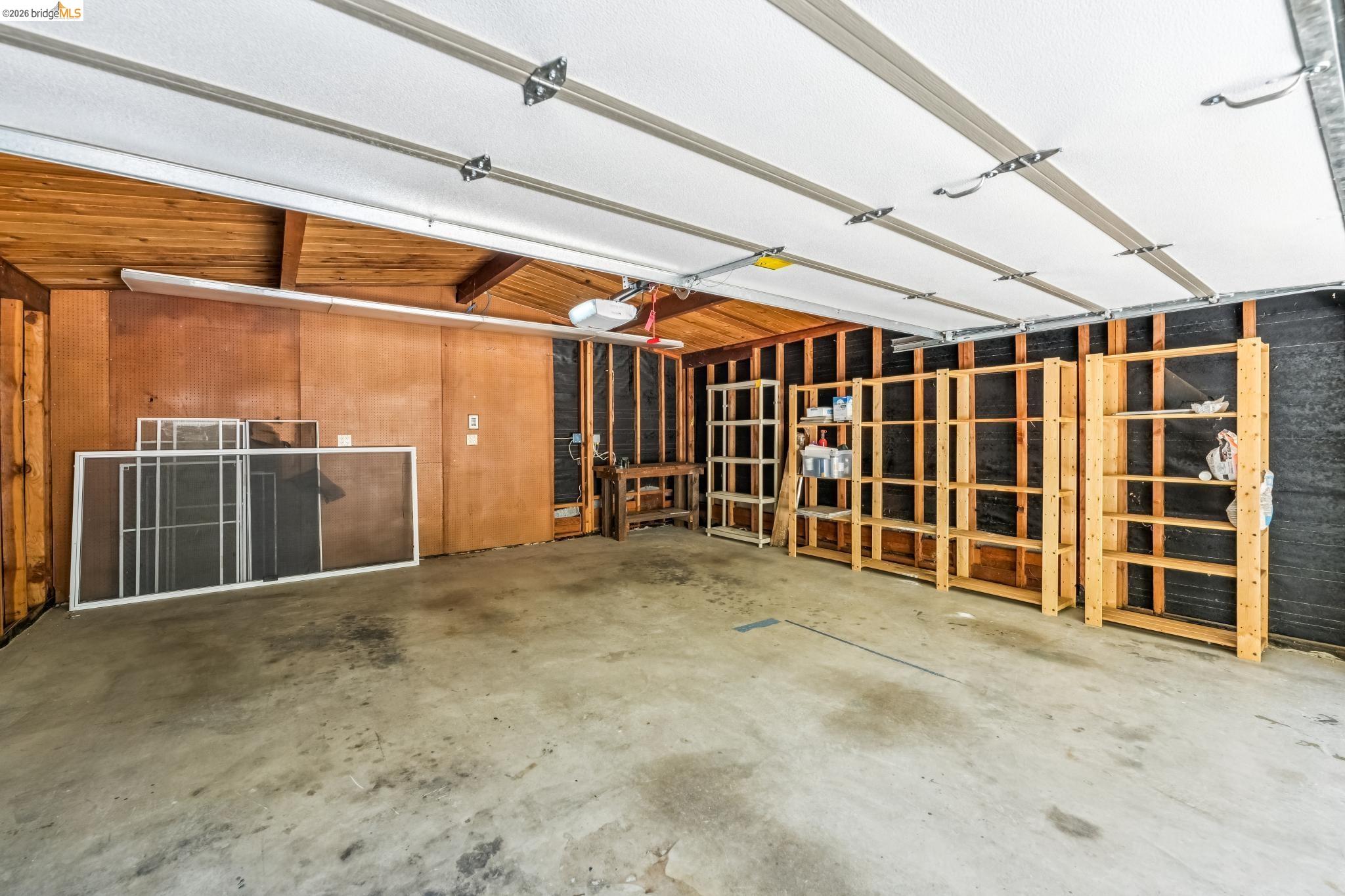 6645 Heather Ridge Way Oakland, CA 94611 - Photo 53 of 61 Spacious garage featuring a concrete floor, exposed wood ceiling, and paneling on one wall