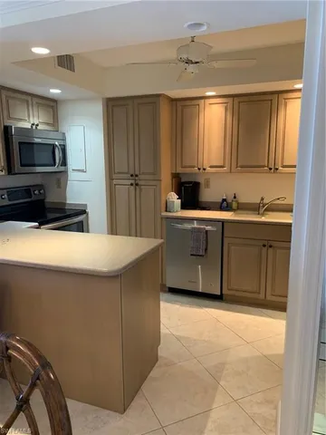 a kitchen with stainless steel appliances a sink a stove a refrigerator cabinets and a window