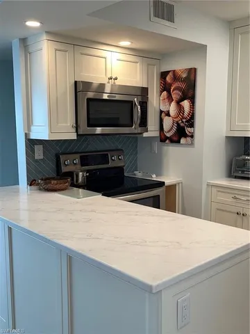 a kitchen with stainless steel appliances a stove a microwave and white cabinets