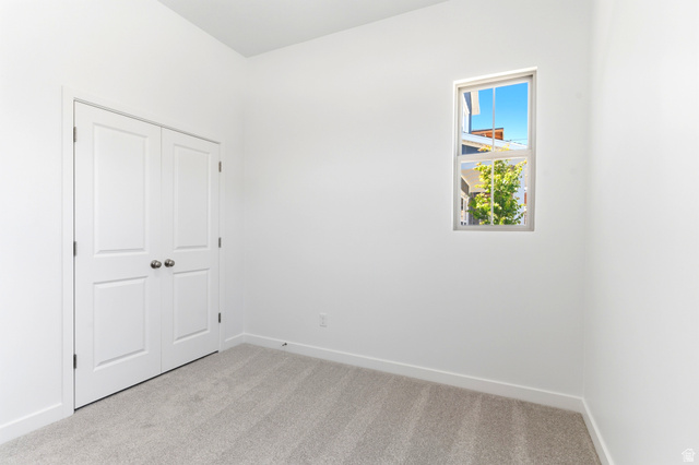 7243 West Terraine Road West Jordan, UT 84081 - Photo 23 of 31 Light-filled room featuring neutral carpeting, white walls, and a single-hung window with a tree backdrop