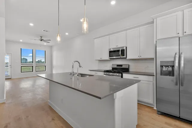 a kitchen with stainless steel appliances granite countertop a refrigerator a sink a stove and oven