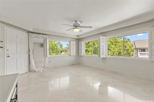 an empty room with windows and ceiling fan