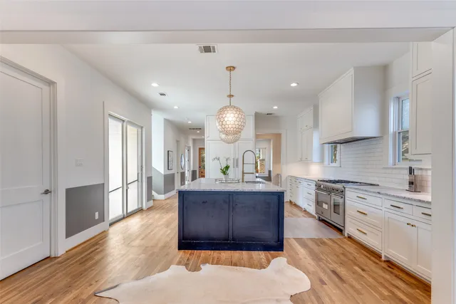 a large kitchen with stainless steel appliances granite countertop a stove a sink dishwasher and a refrigerator with wooden floor