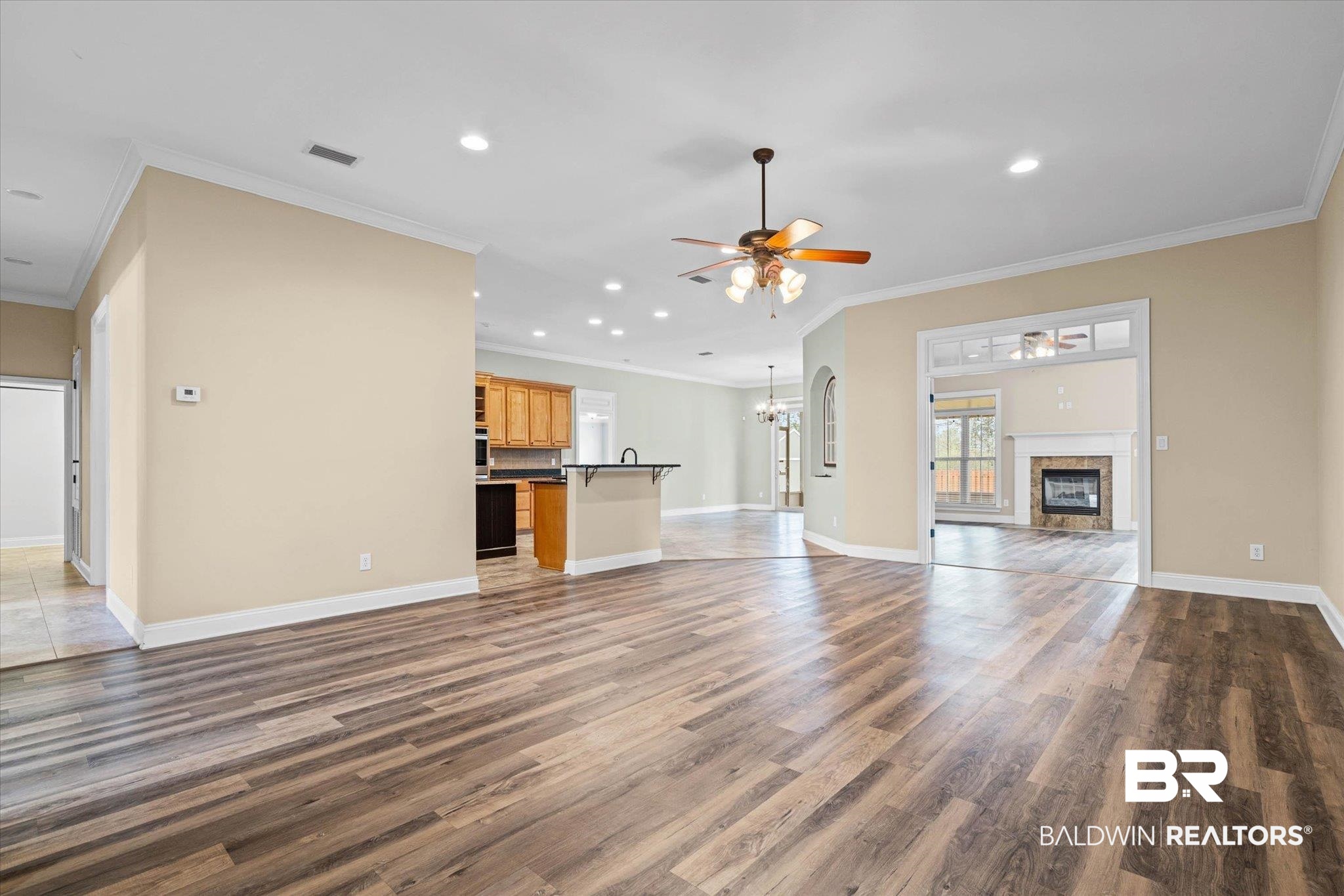 704 Edinburgh Avenue Foley, AL 36535 - Photo 6 of 32 Unfurnished living room with ceiling fan, a tiled fireplace, dark wood-type flooring, hanging lights, and crown molding