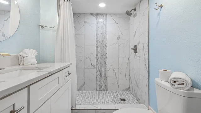 a bathroom with a granite countertop sink a toilet and shower