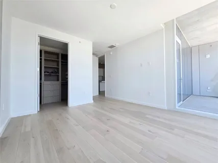 a view of an empty room with wooden floor and closet
