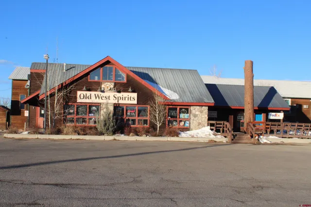 a view of a house with large trees and outdoor seating