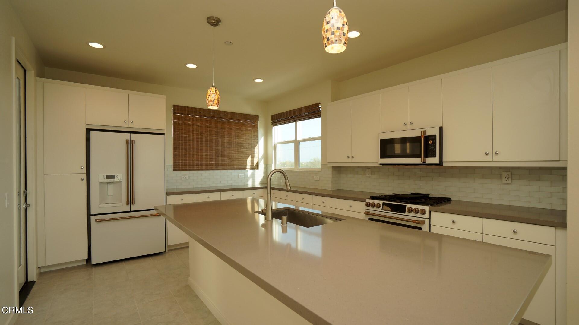 1063 Canal Street Oxnard, CA 93035 - Photo 7 of 32 a kitchen with stainless steel appliances granite countertop a refrigerator a stove and a sink with wooden floor