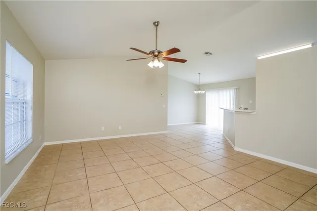 a view of an empty room and a ceiling fan and window