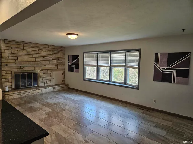 an empty room with windows and fireplace