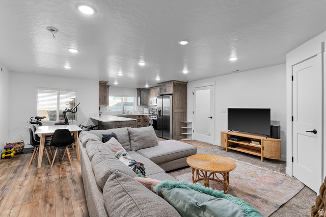 1426 South 1450th Street West Mapleton, UT 84664 - Photo 32 of 50 Open-concept living area featuring wood-finish flooring, recessed lighting, white walls, and a kitchen with wood cabinetry and light-colored countertops