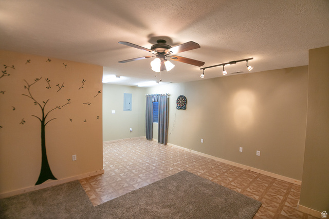 348 North Jakes Pl Road Loa, UT 84747 - Photo 15 of 26 Unfurnished open room featuring track lighting, a ceiling fan, light flooring, a textured ceiling, and electric panel