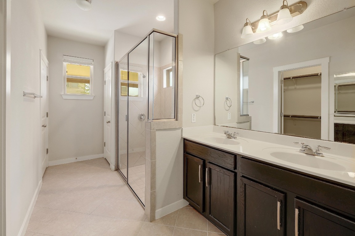 16233 Travesia Way Austin, TX 78728 - Photo 14 of 27 a bathroom with a double vanity sink and mirror with shower