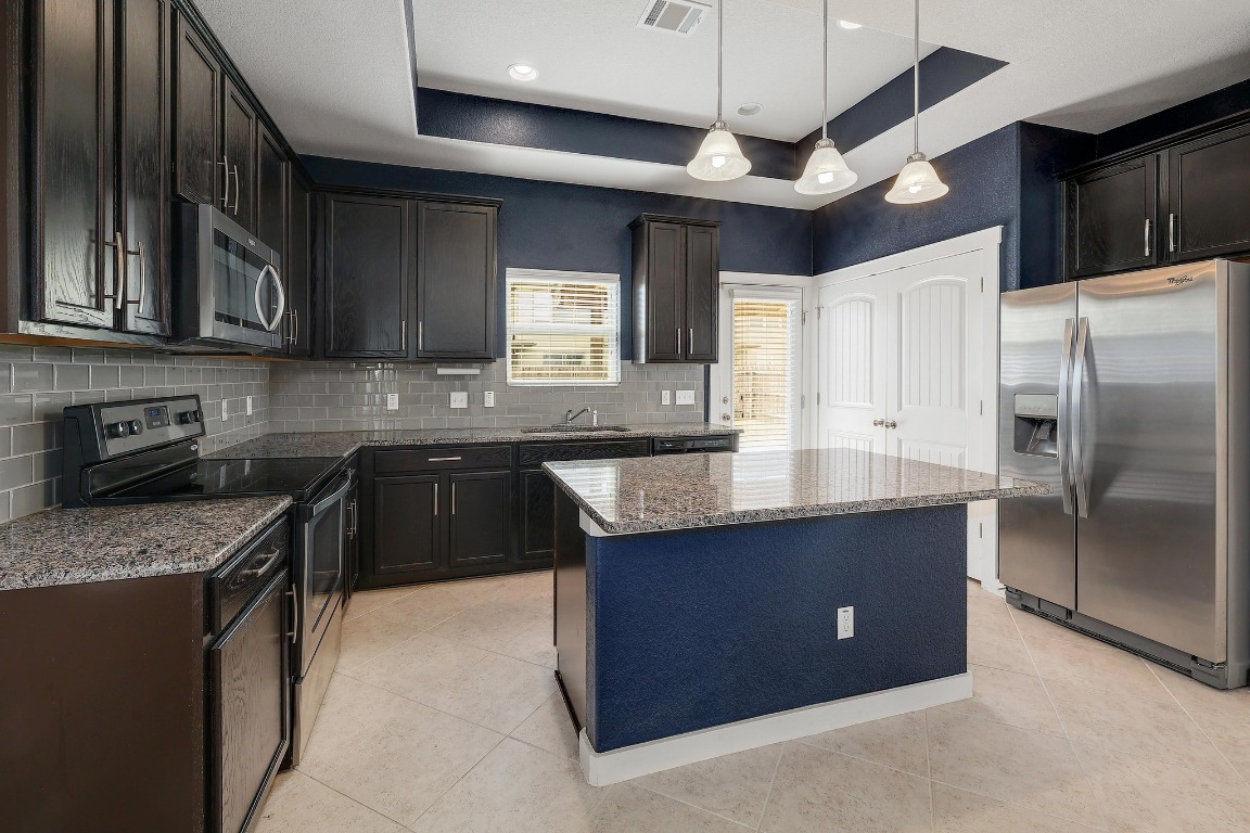 16233 Travesia Way Austin, TX 78728 - Photo 8 of 27 a kitchen with stainless steel appliances granite countertop a sink stove and refrigerator