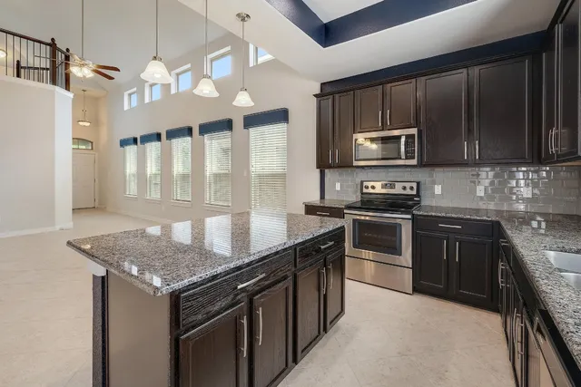 a kitchen with stainless steel appliances granite countertop a stove microwave and sink