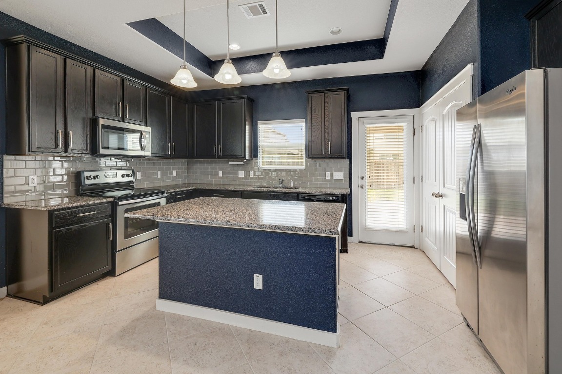 16233 Travesia Way Austin, TX 78728 - Photo 10 of 27 a kitchen with stainless steel appliances granite countertop a stove a sink and a refrigerator