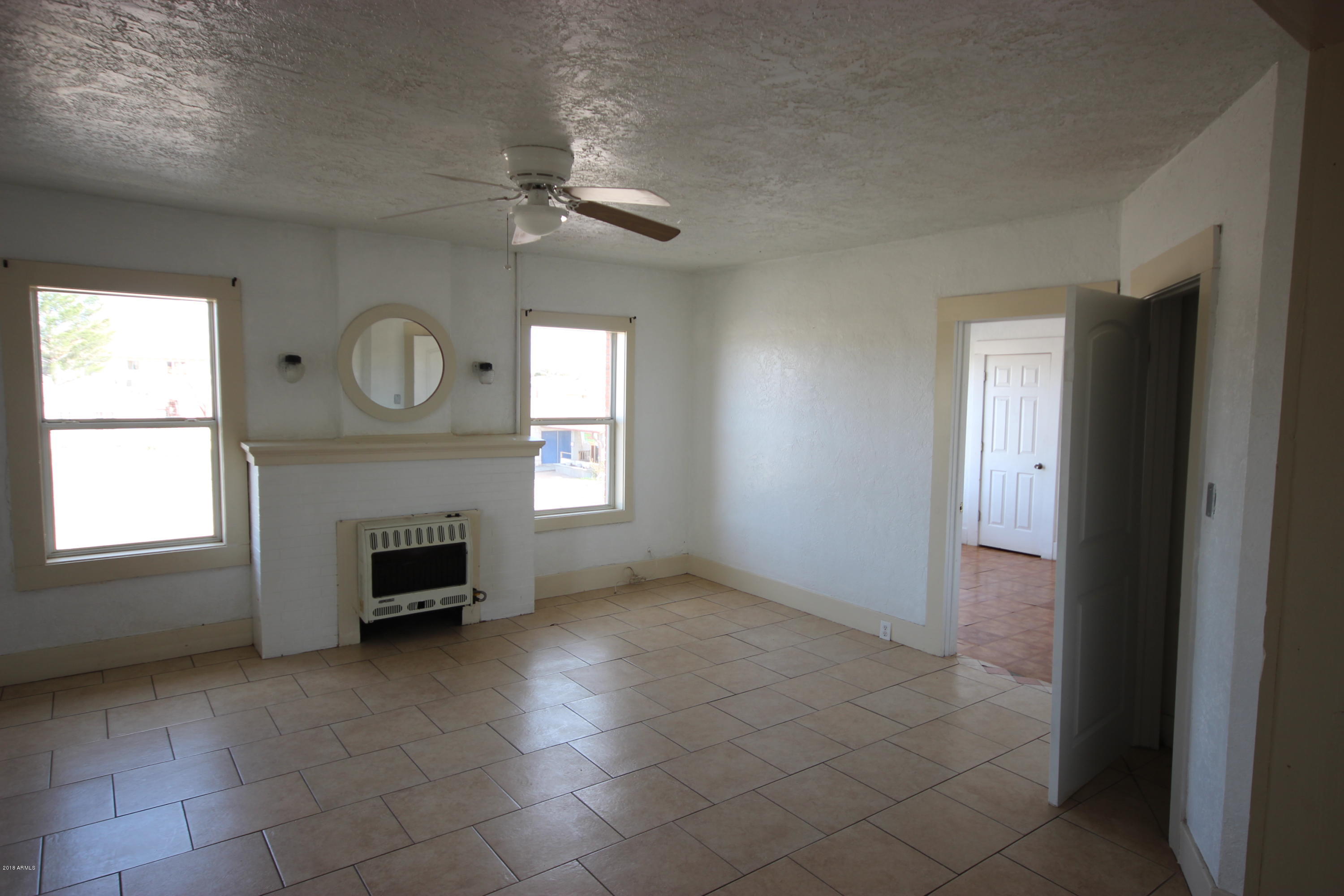 1165 East 10th Street Douglas, AZ 85607 - Photo 12 of 54 an empty room with windows fireplace and fans