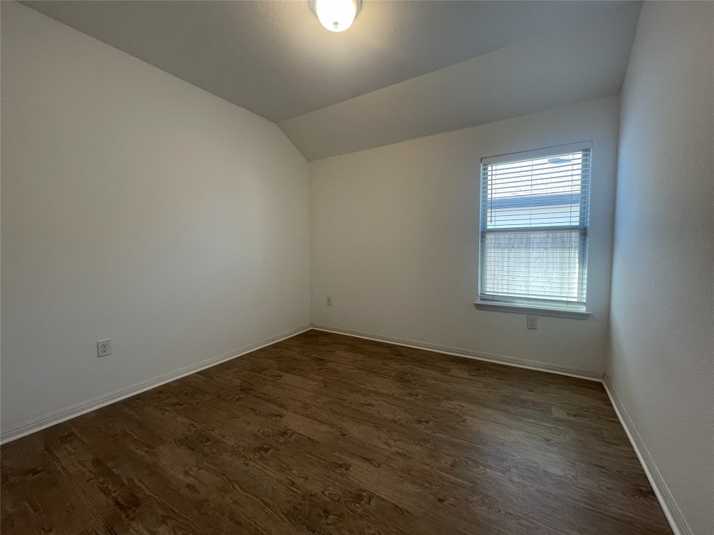 308 Somerville Street Leander, TX 78641 - Photo 12 of 24 Empty room featuring vaulted ceiling and dark wood finished floors