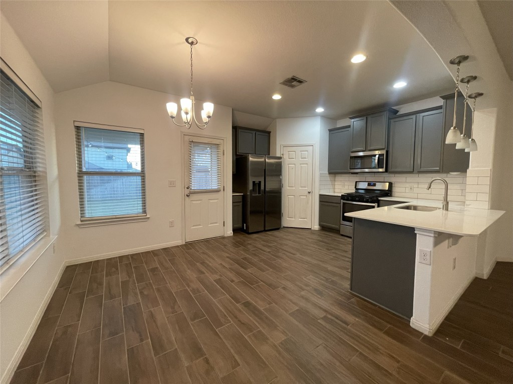 308 Somerville Street Leander, TX 78641 - Photo 3 of 24 Kitchen with hanging light fixtures, tasteful backsplash, stainless steel appliances, gray cabinets, and vaulted ceiling