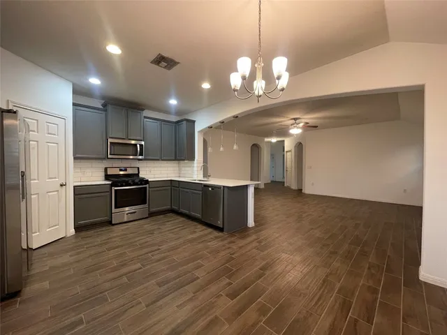 a kitchen with stainless steel appliances granite countertop a sink a refrigerator and a stove top oven