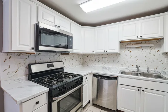 a kitchen with granite countertop white cabinets stainless steel appliances and a sink