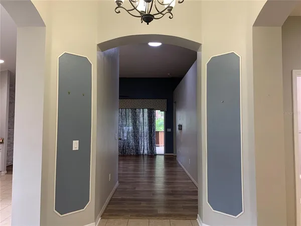 an empty room with wooden floor chandelier fan and windows